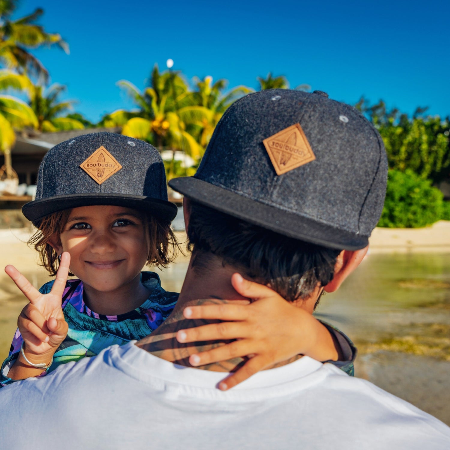 Vater und Tochter tragen Caps am Strand