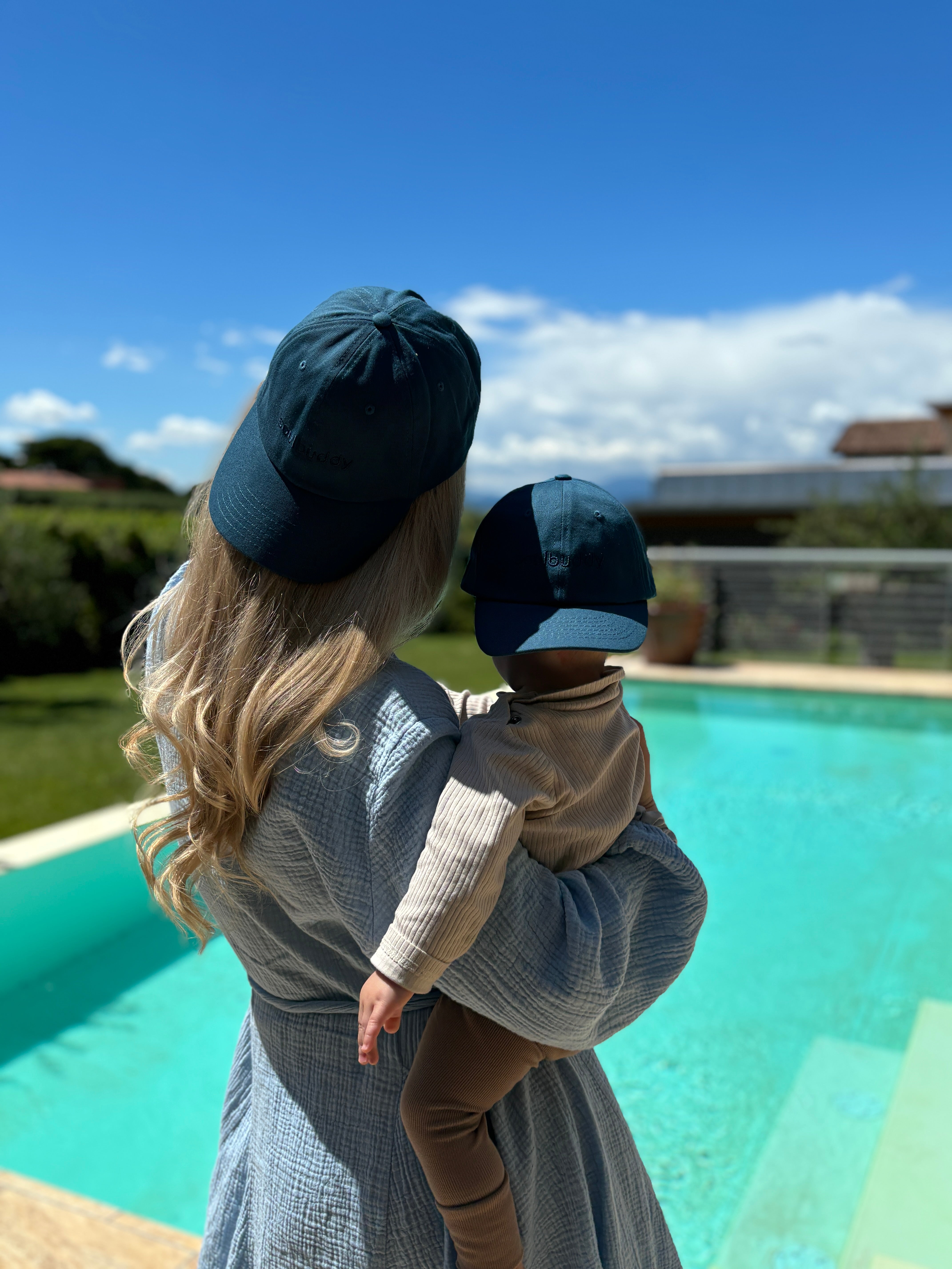 Mutter mit Kind trägt Partnerlook Caps am Pool