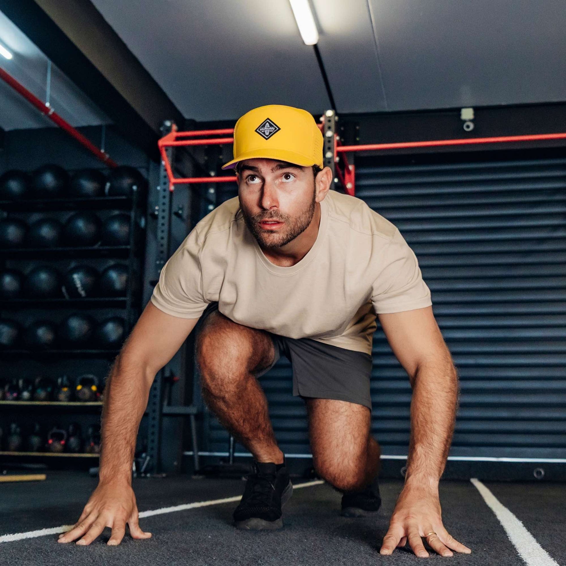Sportlicher Mann trägt gelbe Performance Snapback Cap beim funktionellen Training im Fitnessstudio in Startposition