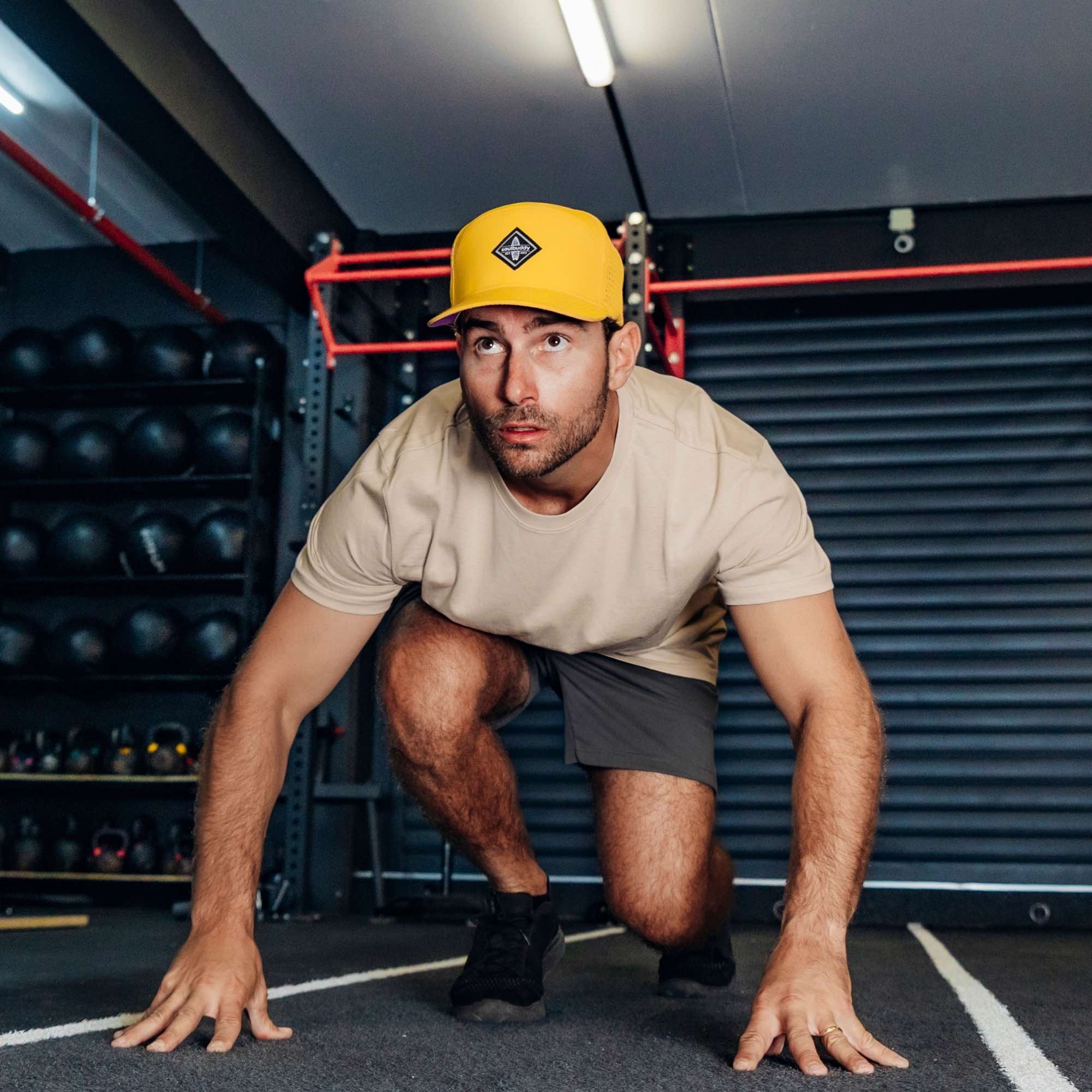 Sportlicher Mann trägt gelbe Performance Snapback Cap beim funktionellen Training im Fitnessstudio in Startposition