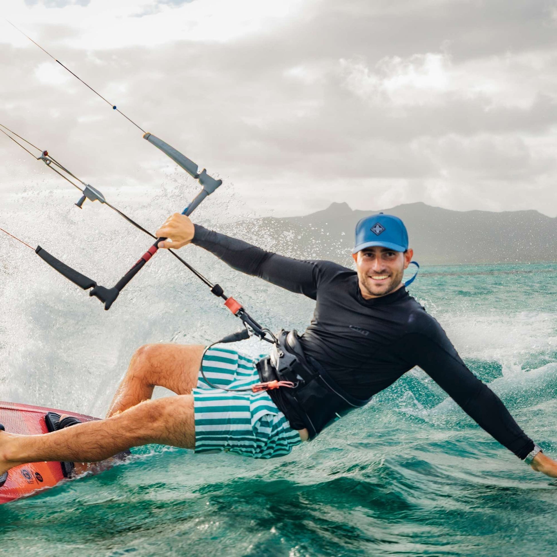 Sportlicher Mann trägt blaue Performance Snapback Cap beim Kitesurfen auf dem Meer bei dynamischen Bedingungen