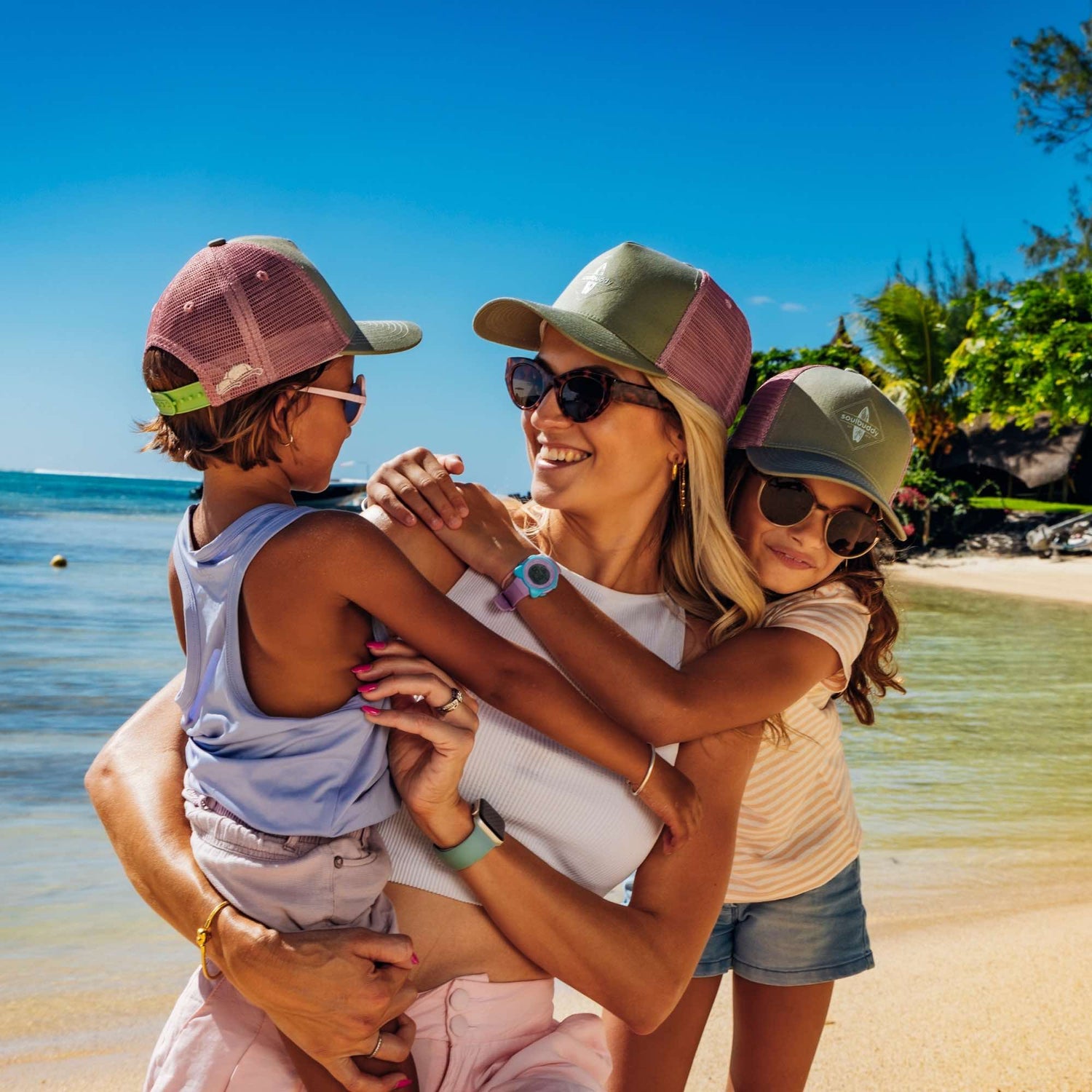 Mutter mit Töchtern tragen rosa-grüne Trucker Cap am Strand